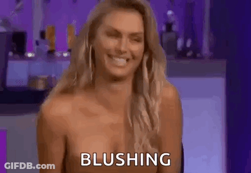 A Naked Woman Is Smiling And Blushing While Sitting On A Chair . GIF