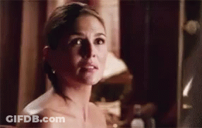 A Naked Woman Is Standing In Front Of A Mirror Looking At Herself . GIF