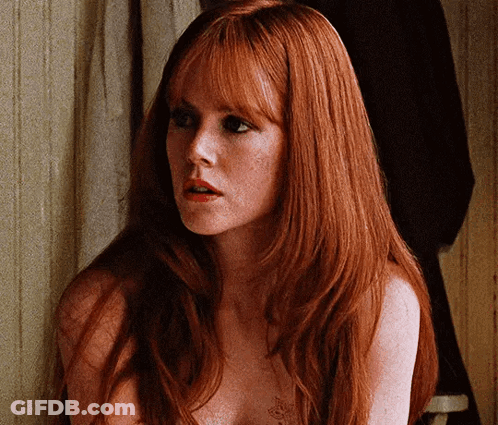 A Naked Woman With Long Red Hair And Freckles Is Looking At The Camera GIF