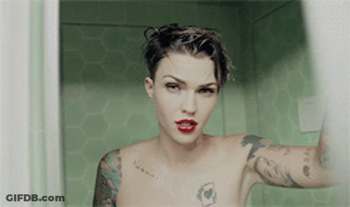 A Naked Woman With Tattoos On Her Arms And Chest Is Taking A Selfie GIF
