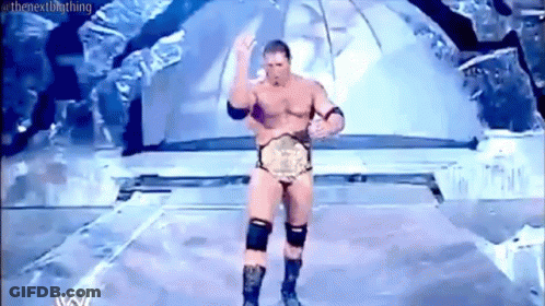 A Naked Wrestler Is Standing On A Stage With A Wrestling Championship Belt . GIF