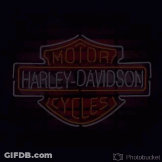 A Neon Sign For Harley Davidson Cycles On A Red Background GIF