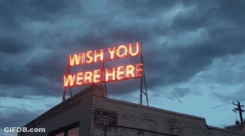 A Neon Sign On Top Of A Building Says " Wish You Were Here " GIF