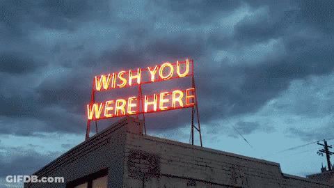 A Neon Sign On Top Of A Building Says " Wish You Were Here " GIF