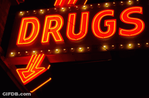 A Neon Sign That Says " Drugs " Is Lit Up At Night GIF