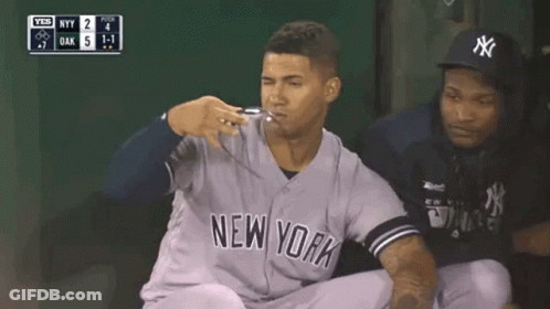 A New York Yankees Baseball Player Is Kneeling Down In The Dugout During A Game . GIF