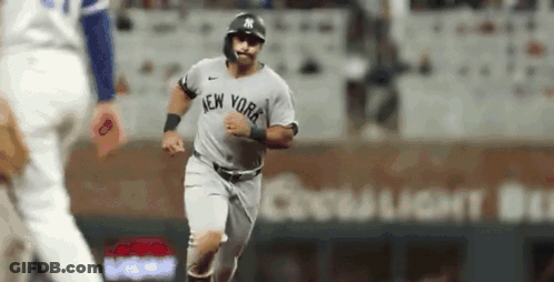 A New York Yankees Baseball Player Is Running On The Field During A Baseball Game . GIF