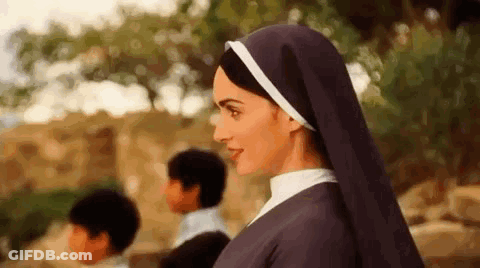 A Nun Is Standing In Front Of A Group Of Children In A Field . GIF