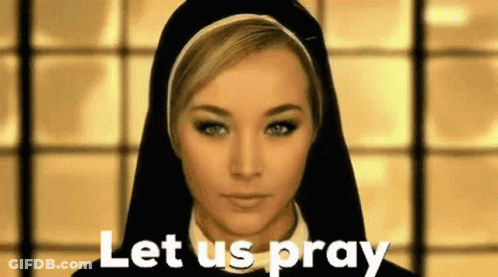 A Nun Is Standing In Front Of A Window And Says Let Us Pray . GIF