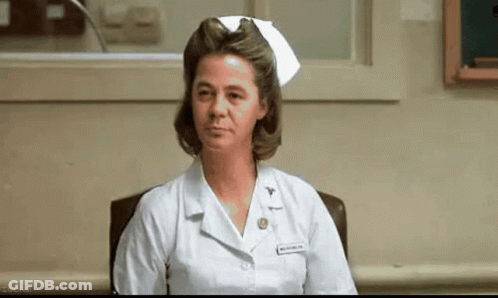 A Nurse Is Sitting In A Chair In A Hospital Room Wearing A White Nurse 'S Cap . GIF