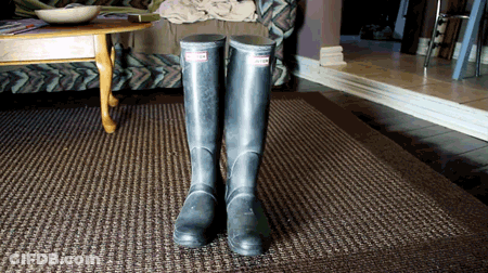 A Pair Of Black Hunter Boots Are On A Rug GIF