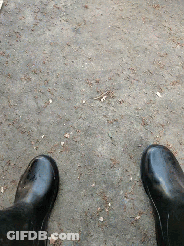 A Pair Of Black Rubber Boots Standing On A Concrete Surface GIF