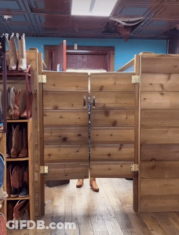 A Pair Of Cowboy Boots Are Hanging On A Shelf Next To A Wooden Door GIF