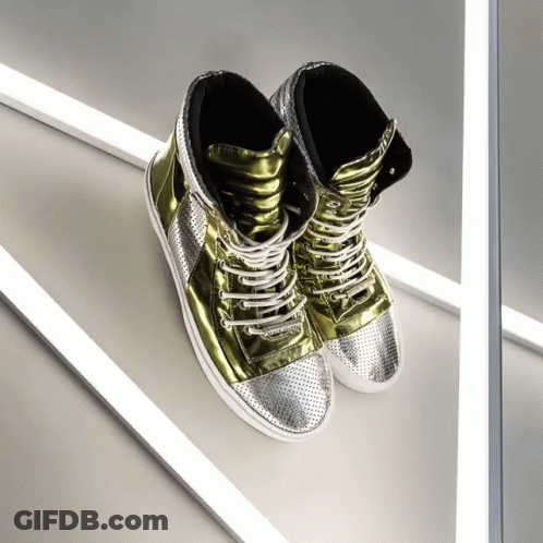 A Pair Of Gold And Silver High Top Sneakers Are Sitting On A White Surface GIF