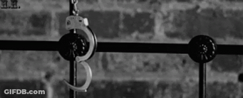 A Pair Of Handcuffs Hanging From A Metal Railing . GIF