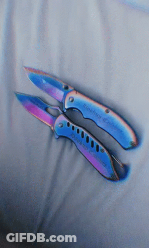 A Pair Of Knives With A Rainbow Colored Handle Are Laying On A White Cloth GIF