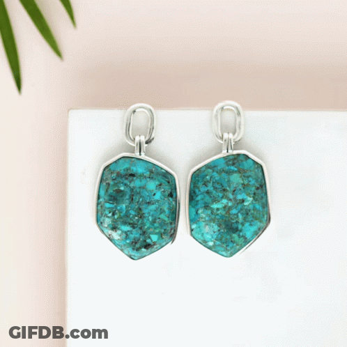 A Pair Of Turquoise Earrings Are Sitting On A Table GIF