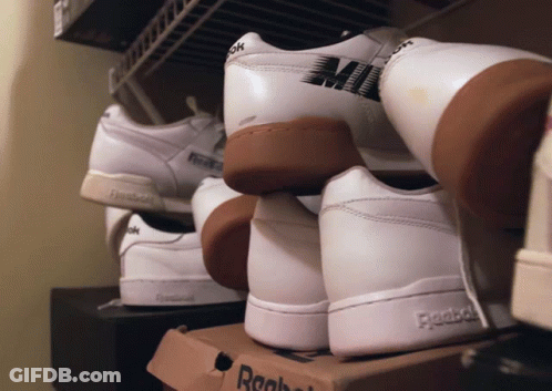 A Pair Of White Reebok Shoes Are Stacked On Top Of A Cardboard Box GIF