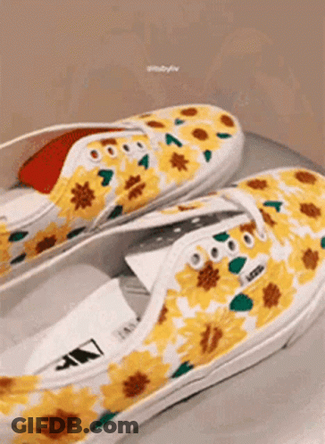 A Pair Of Yellow And White Vans Shoes With Sunflowers Painted On Them . GIF