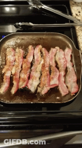 A Pan Of Bacon Is Being Cooked On A Stove Top GIF