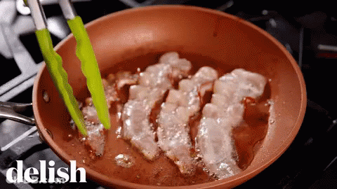 A Pan Of Bacon Is Being Cooked On A Stove With The Word Delish In The Upper Right Corner GIF
