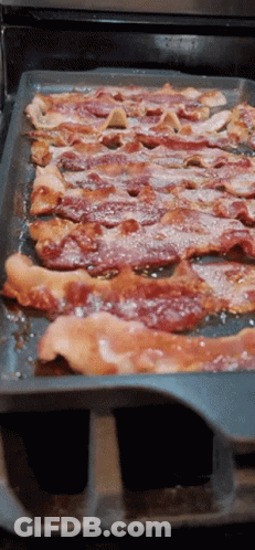 A Pan Of Bacon Is Sitting On A Stove Top GIF
