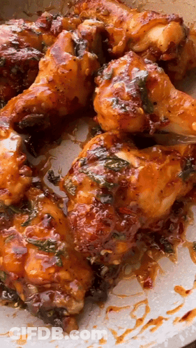 A Pan Of Chicken Wings With Sauce On Them GIF
