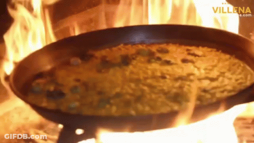A Pan Of Food Is Being Cooked On A Fire With The Website Villena.com Visible In The Corner GIF