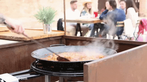 A Pan Of Food Is Being Stirred By A Person GIF