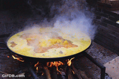 A Pan Of Food Is Cooking On A Fire GIF