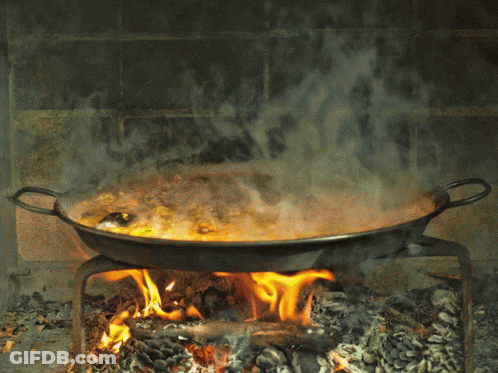 A Pan Of Food Is Cooking Over A Fire In A Fireplace GIF