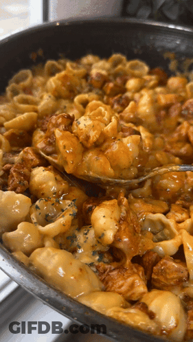 A Pan Of Macaroni And Cheese With A Fork In It GIF