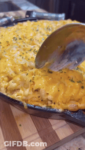 A Pan Of Macaroni And Cheese With A Spoon In It GIF