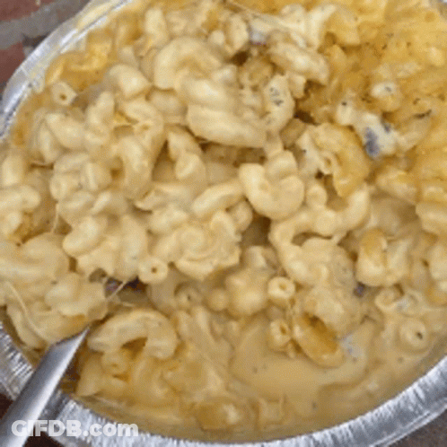 A Pan Of Macaroni And Cheese With A Spoon In It GIF