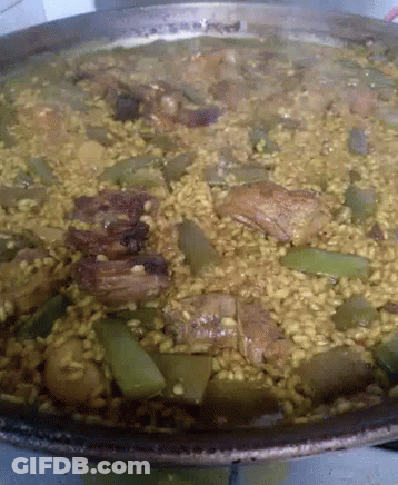 A Pan Of Rice With Meat And Vegetables Is Being Cooked GIF