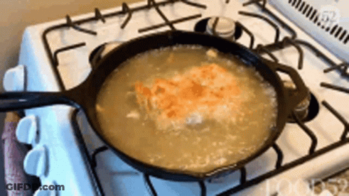 A Pan Of Soup Is Cooking On A Stove Top GIF