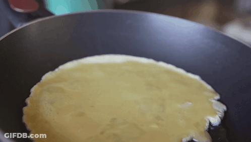 A Pancake Is Being Cooked In A Frying Pan With Oil . GIF