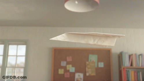 A Paper Airplane Is Flying In Front Of A Bulletin Board That Says " The Aviator " On It GIF