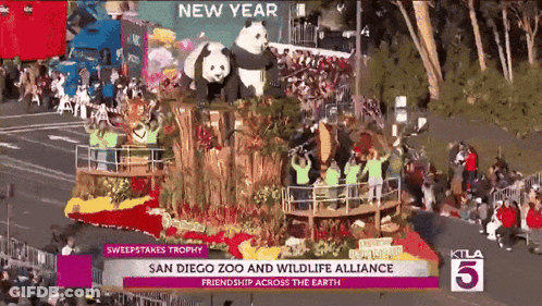 A Parade With A Float That Says ' San Diego Zoo And Wildlife Alliance Friendship Across The Earth ' On It GIF