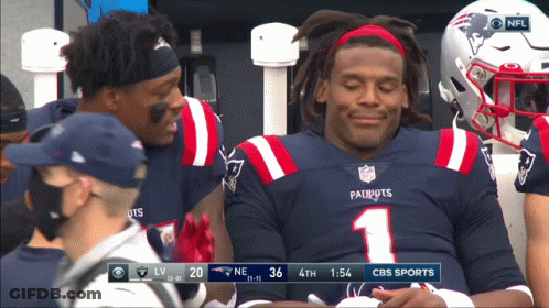A Patriots Football Player Is Smiling While Sitting On The Bench GIF