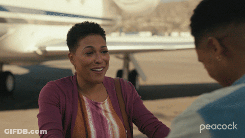 A Peacock Ad Shows Two Women Talking In Front Of A Plane GIF
