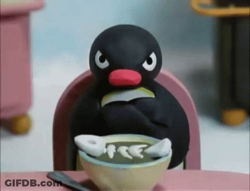A Penguin Is Sitting At A Table With A Bowl Of Soup In Front Of Him GIF