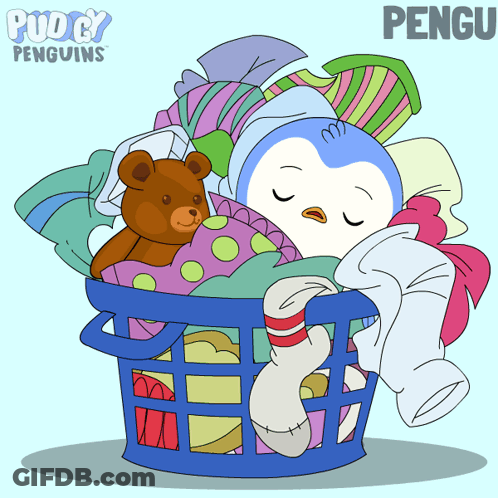 A Penguin Is Sleeping In A Laundry Basket With Clothes And A Teddy Bear GIF