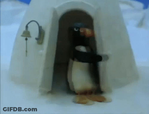 A Penguin Standing In Front Of An Igloo With A Bell On It GIF