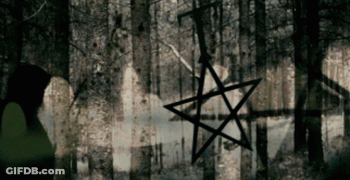A Pentagram Is Hanging From A Tree In The Dark GIF