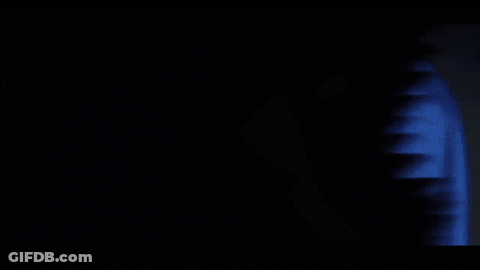 A Person Covering Their Face With Their Hand While A Red Light Shines On Them GIF