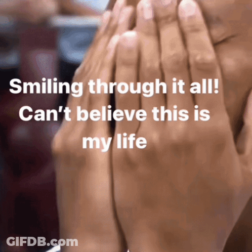 A Person Covering Their Face With Their Hands With The Words Smiling Through It All GIF