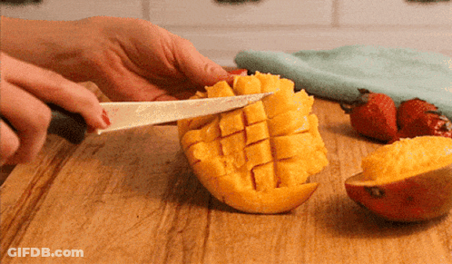 A Person Cutting A Mango On A Cutting Board GIF