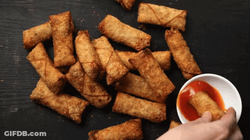 A Person Dipping A Fried Egg Roll In A Bowl Of Sauce GIF