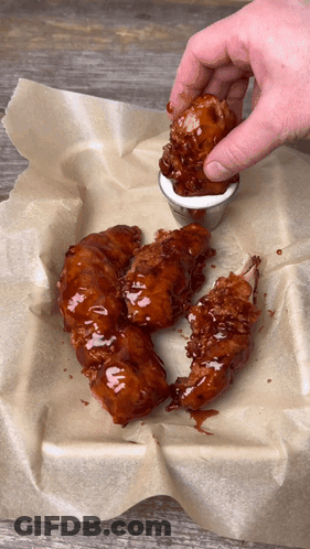 A Person Dipping A Piece Of Chicken Into A Sauce GIF